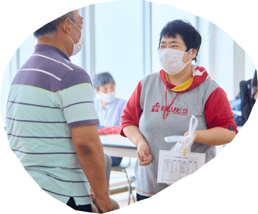 職員が利用者に袋を手渡しながら会話している写真