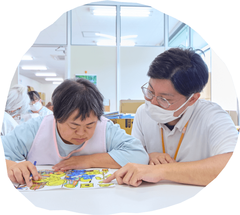 職員と利用者が一緒に塗り絵を楽しんでいる写真